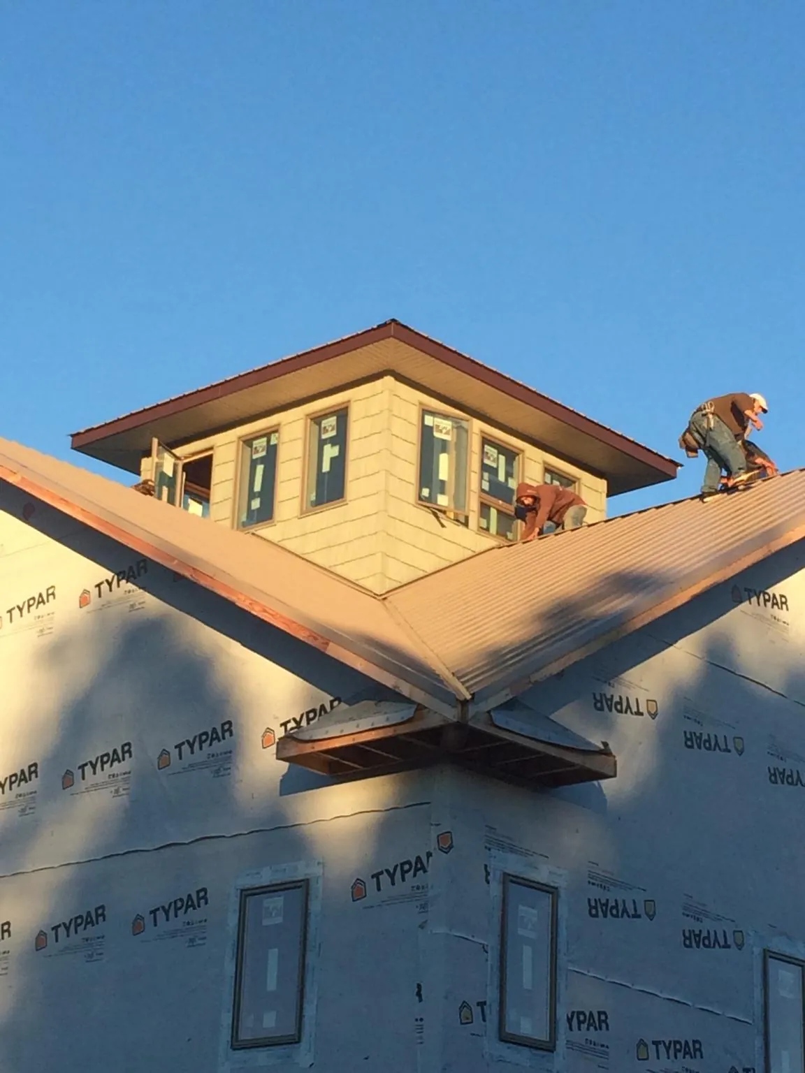 Roofers working around a rooftop cupola on a new metal roof at sunset — Roof Waterproofing in Newton by Roofing Brothers